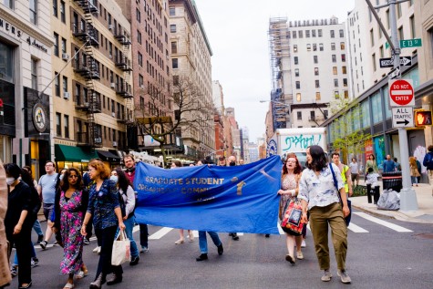 Protesters walk down University Place holding a large blue sign.