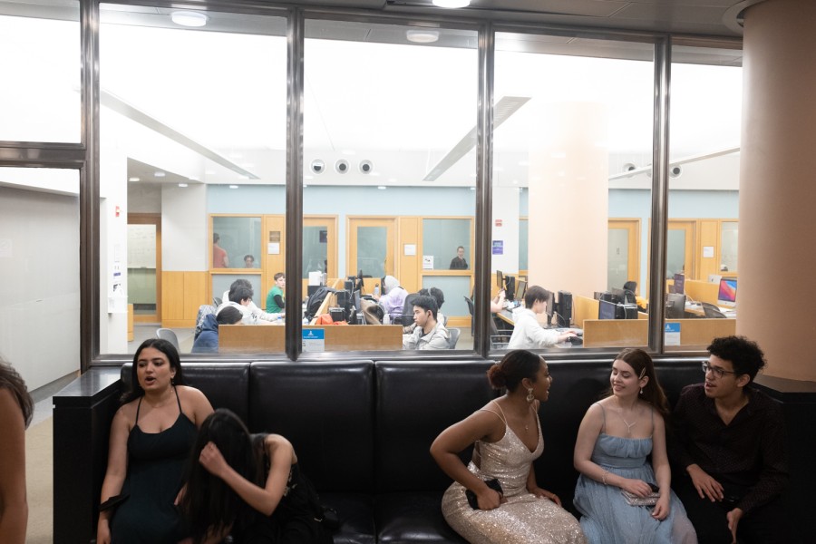 Students dressed in formal attire in the foreground and a study lounge filled with students in the background.