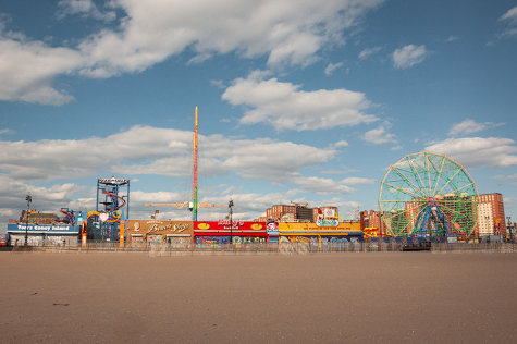 The Luna Park amusement rides on Coney Island as seen from the beach. On the right, a ferris wheel towers over surrounding buildings.