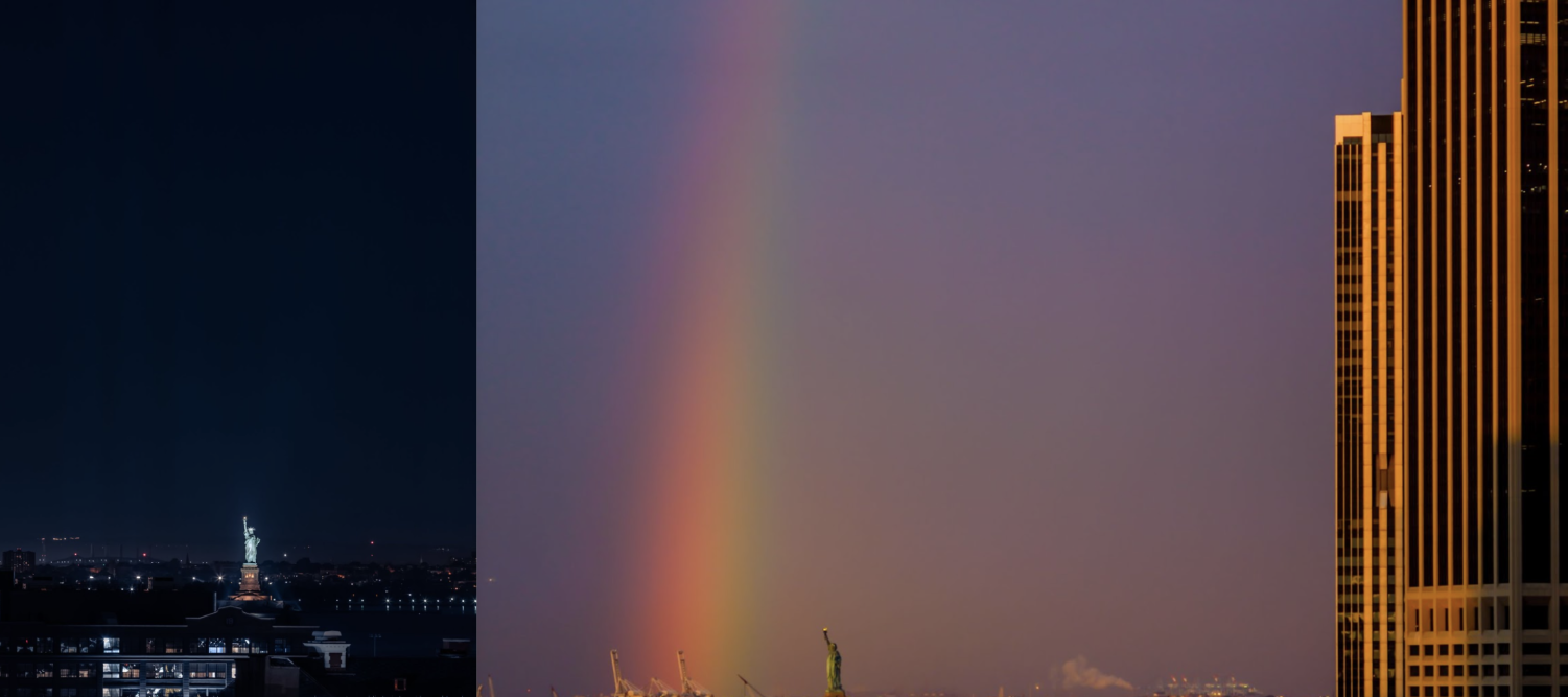 The Statue of Liberty during night time. A rainbow to the left; the Statue of Liberty at the bottom and white office building cast in golden sunrise light to the right.