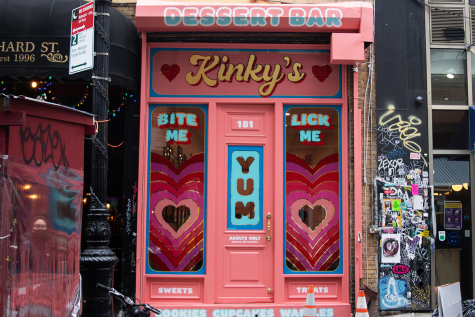 The bubblegum pink storefront of Kinky’s Dessert Bar. On either side of the door, hearts are printed on the windows in a range of pink tones. Above the door is the word “Kinky’s” in yellow letters.
