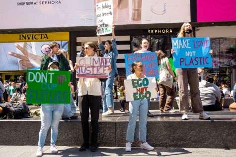 Nine protesters holding signs and megaphones in Times Square.