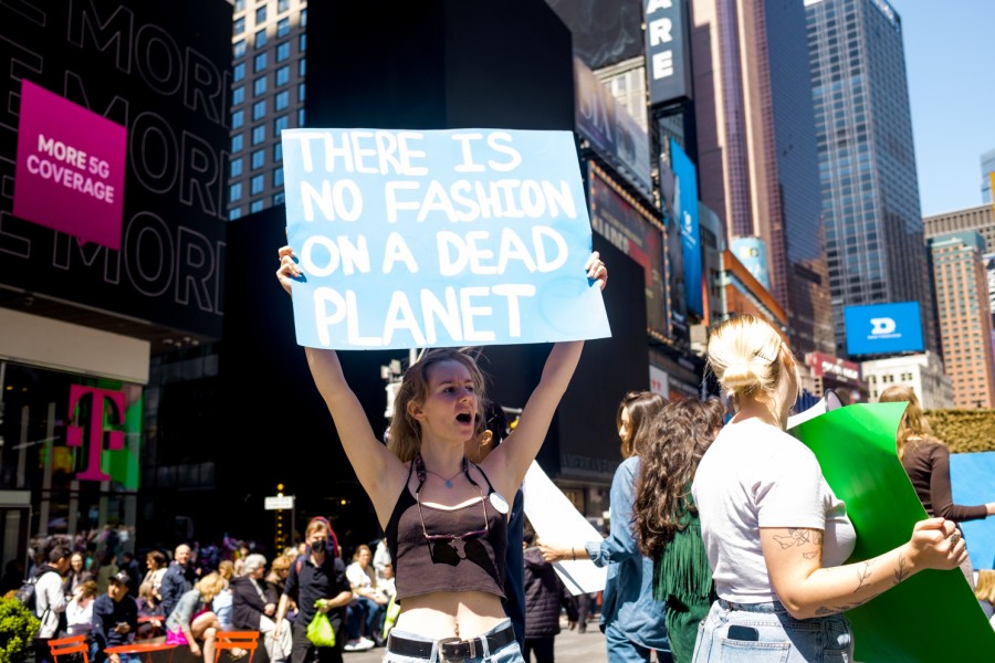 A protester shouting while holding a sign reading “There is no fashion on a dead planet” in Times Square.