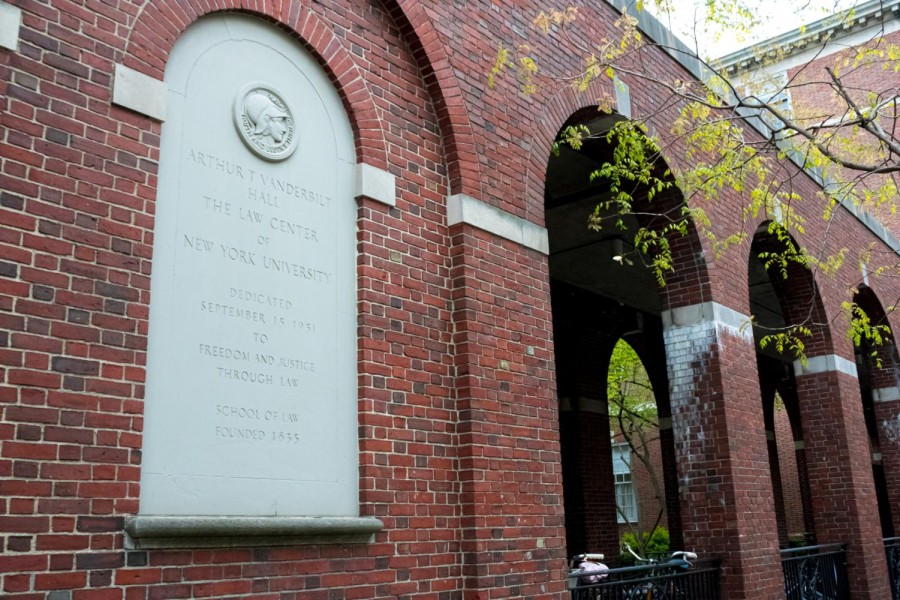 The brick exterior of NYU’s law school. Arches frame the courtyard, and an engraved stone sign bears the law school’s name.