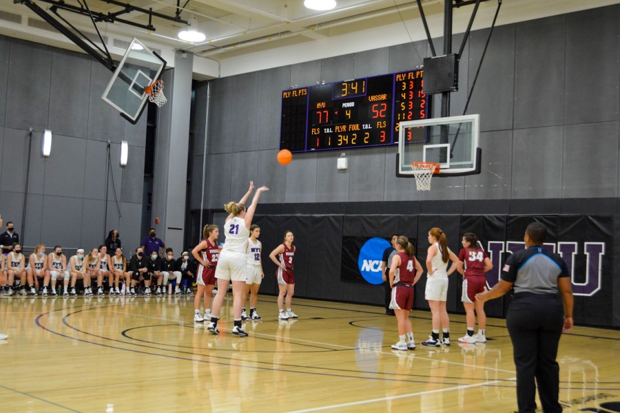 A picture of Meghan McLaughlin throwing a ball into a basketball hoop with her arms raised.