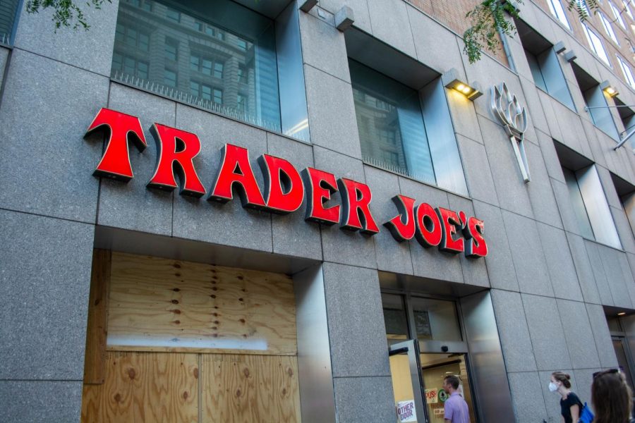 A vertical view of the facade of Trader Joe’s and its red font sign. To the right of the Trader Joe’s is Palladium Hall.
