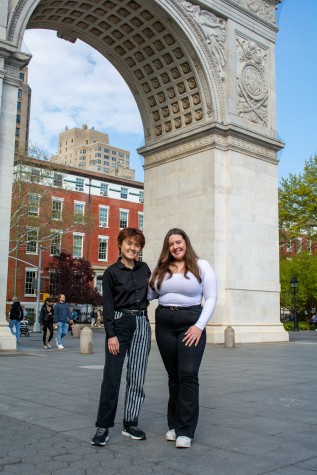 Portrait of Caitlin Hsu and Sydney Barragan in front of the Washington Square Arch in a sunny light.