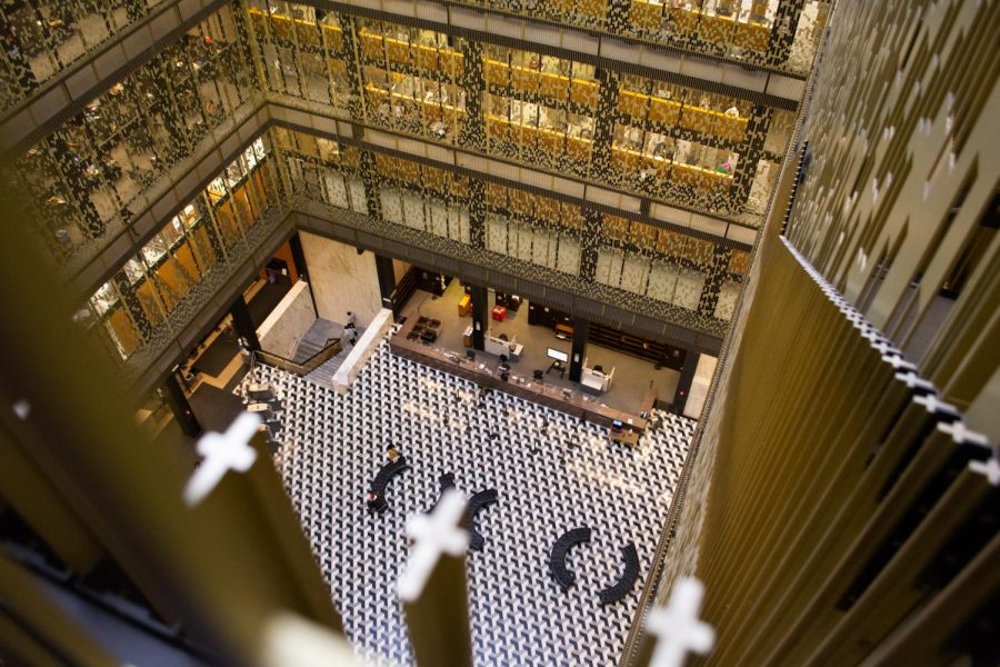 An image of Bobst Library, looking down on the ground-floor atrium. On each level, metal screens run from the floor to the ceiling.