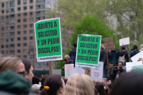 People hold signs at an abortion rights protest at Foley Square. The signs are green and they read “¡ABORTO A SOLICITUD Y SIN PEDIR DISCULPAS!”