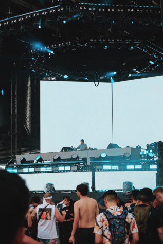 A crowd listening to Rome in Silver, a DJ, performing on a blue-themed stage.