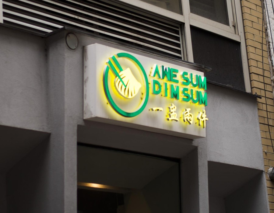 A lit-up yellow and green sign of “Awe Sum DimSum.”