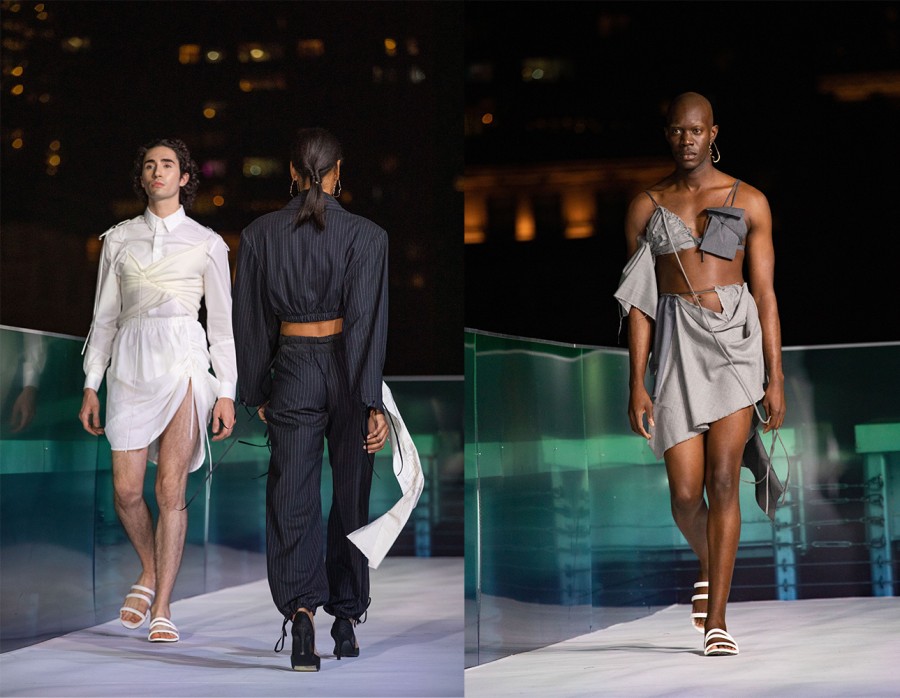 Two models pass each other, one wearing a white dress and the other wearing a black two-piece striped suit; A model walking down the aisle wearing a gray ensemble.