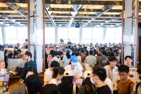 Hundreds of students pack a room with tables and signs.
