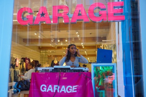 A DJ looking at a desktop with a sign above that reads “Garage” in pink.
