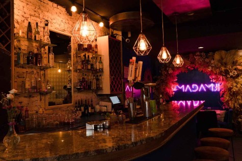 A dimly lit bar with a neon purple sign in the background.