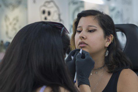 Ericka Vinefog marks Tori Morales' lower lip with a blue marker.