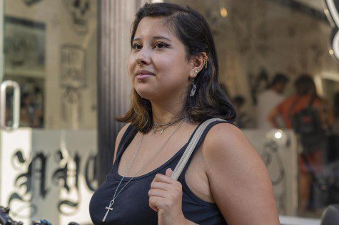 Tori Morales stands in front of piercing shop Live By The Sword Tattoo with their new vertical labret piercing.