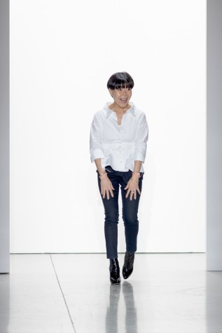 Designer Son Jung Wan dressed in a white blouse, black pants and black heels bows to the audience.
