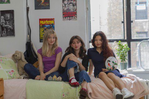 Pictured from left to right are Catherine Desciak, Daisy Brookman and Sophia Wang sitting on Catherine’s bed in their Rubin dorm room. Catherine is wearing a purple t-shirt with dark blue jeans. Daisy is wearing a white t-shirt, black sweater and washed blue jeans. Sophia is wearing a dark blue collared dress. They are all looking at the camera with pleasant expressions.