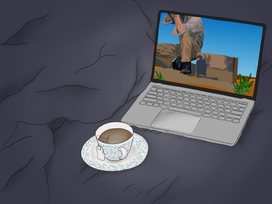 A silver and black laptop shows a scene in a desert with a man squatting. A white and blue cup of tea is in front of the laptop.