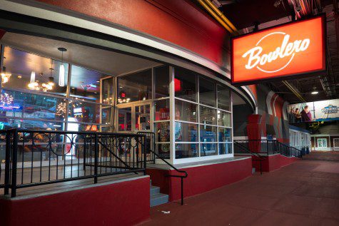 The facade of a building with walls painted red and a light sign with white text “Bowlero” striking through a white circle.