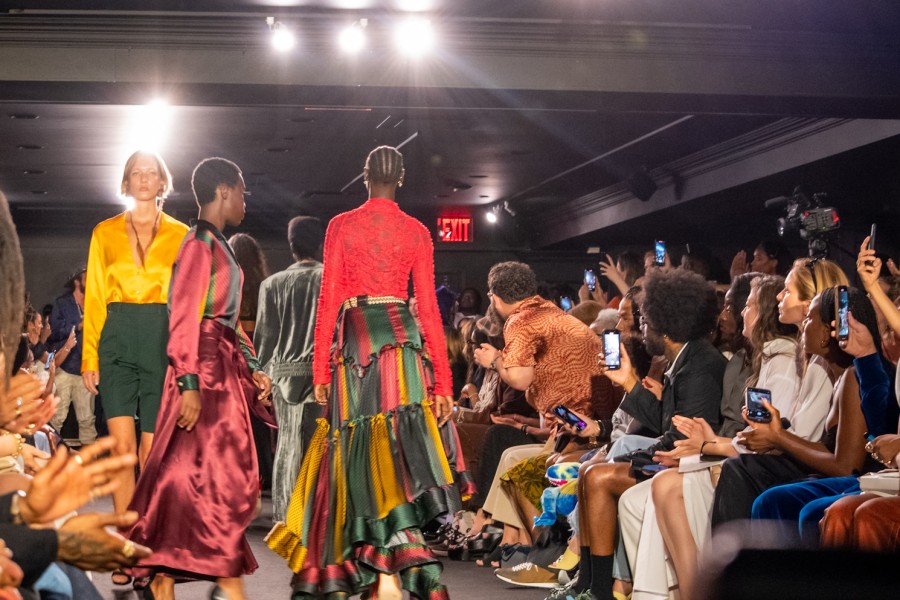 Models wearing clothes in shades of yellow, green, and red walk down anOnlyChild’s New York Fashion Week runway.