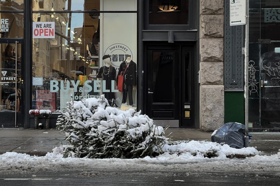 A New York City street in the winter. A pile of garbage covered in snow on the side of the street.