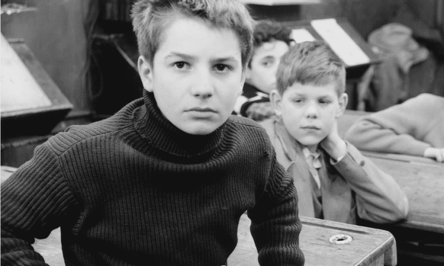 A black-and-white photo of a young boy, dressed in a black turtleneck, staring at the camera.