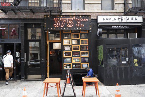 The facade of a restaurant with an orange neon-lit sign that reads “375 degrees CHICKEN N FRIES.”