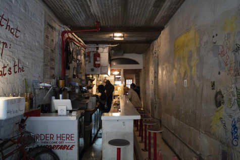 The interior of a restaurant with a long white countertop, and red and white stools.