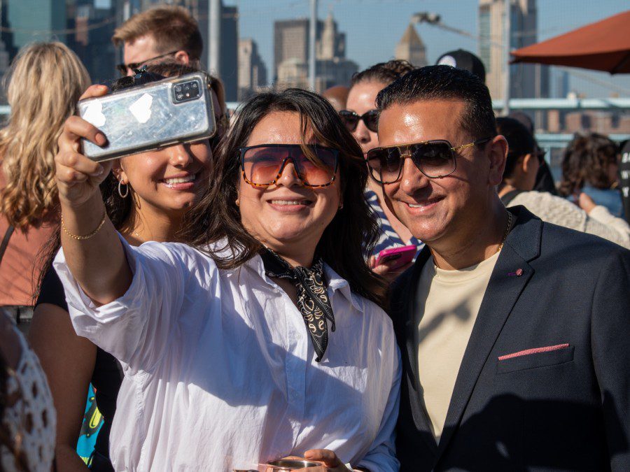 Sofia and Buddy Valastro smile and pose with a woman in a white top for a selfie.