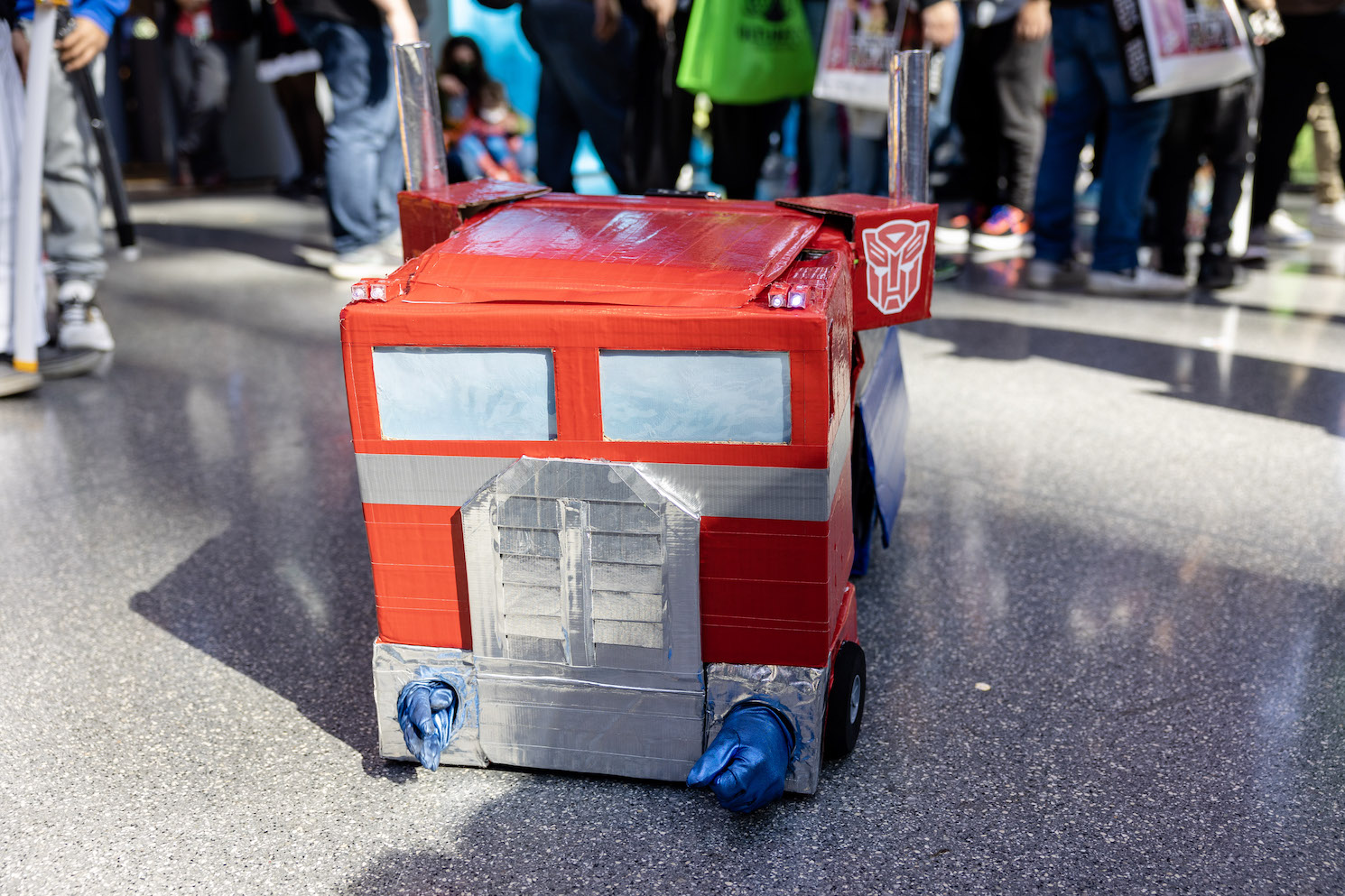 A cosplayer dressed in a cardboard costume of the Transformers character Optimus Prime.