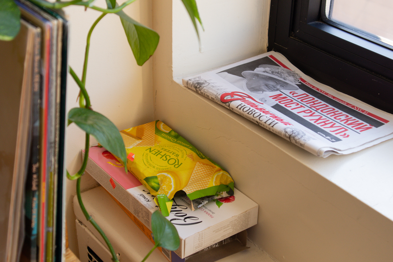 A window ledge with a newspaper and a package of wafers on it.