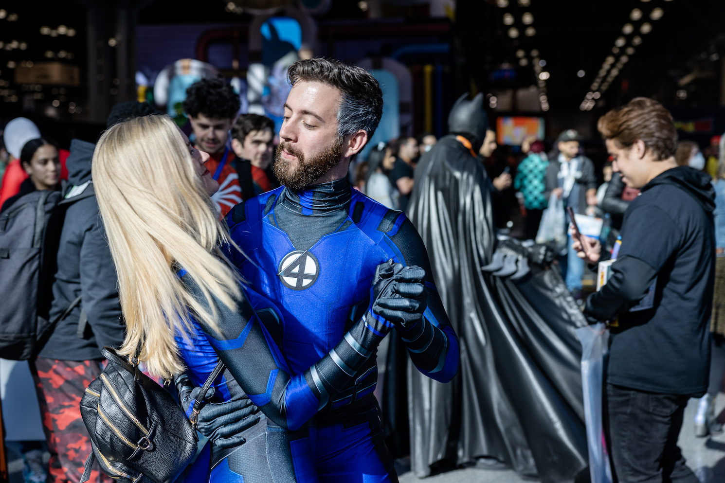 A bearded man in a blue bodysuit with the number four on his chest slow-dances with a blond woman in a matching bodysuit. The couple is dressed in Fantastic Four costumes.