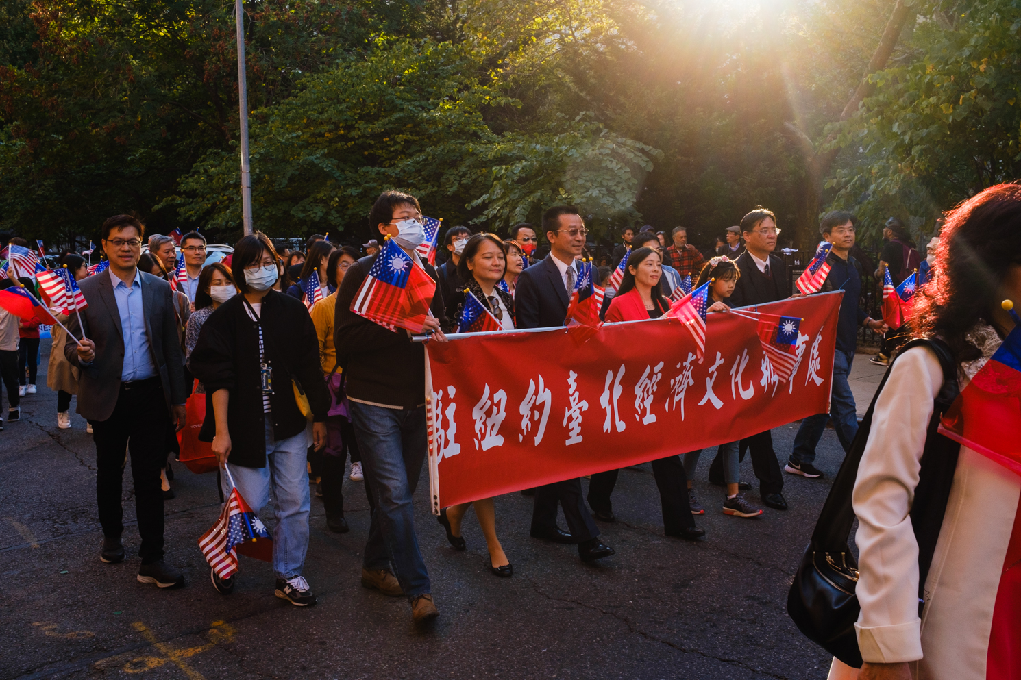 Attendees holding Taiwanese flags and a red banner that translates to “The Taipei Economic and Cultural Office in New York” march down Mulberry Street.
