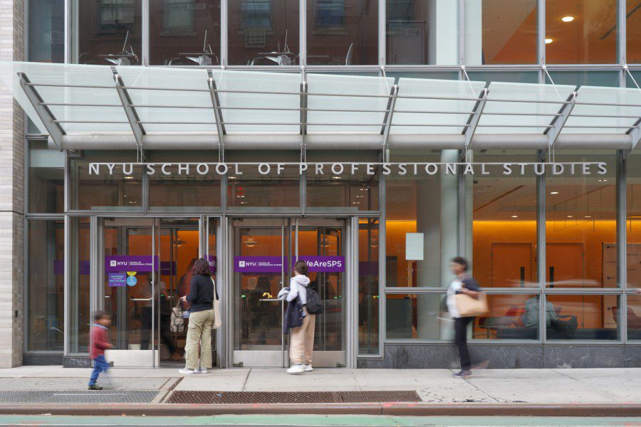 Two people entering the building of New York Univeristys School of Professional Studies with a glass facade.