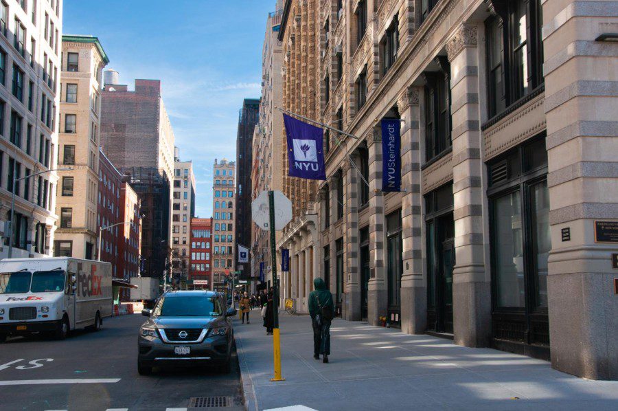 A building which has NYU and NYU Steinhardt flags hoisted from a walls.
