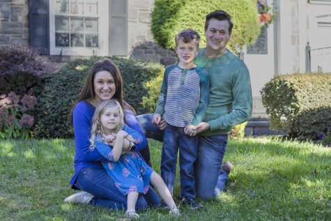 Jessica York, to the left, poses with her daughter, son, and husband, to the right, on their front lawn outside of their home in New Jersey. They are all smiling at the camera.