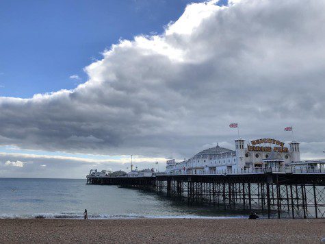 Landscape photo of Brighton, England, featuring a pier boardwalk on the ocean.