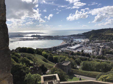 Landscape photo of Dover, England, featuring greenery, small town, and an ocean in the background.