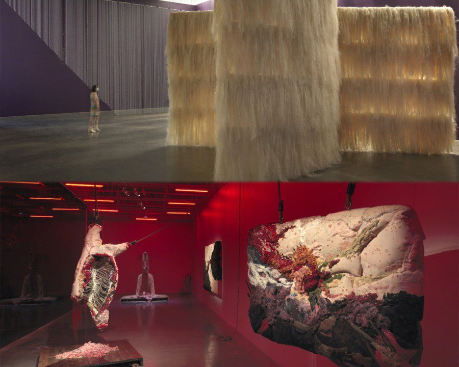 Four large pieces of art on display in an exhibition venue lit up with red light. A large white art installation on display in an exhibition venue with purple walls and white ceiling.