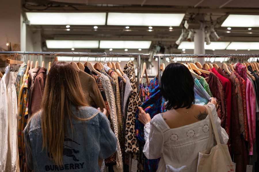 Two shoppers stand in front of a rack of clothes at the Manhattan Vintage Show.