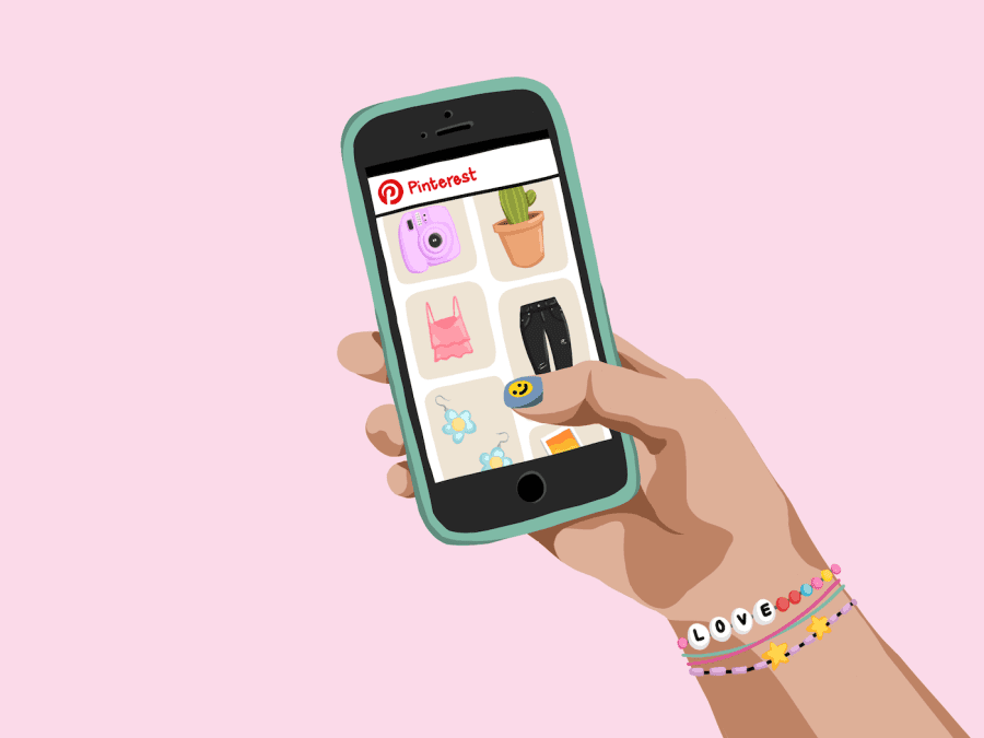 An+illustration+of+a+hand+holding+a+smartphone+which+is+displaying+the+interface+of+the+Pinterest+app%2C+with+graphics+of+a+pink+instant+camera%2C+a+green+cactus%2C+a+pink+vest%2C+a+pair+of+black+jeans+and+a+pair+of+flower+earrings.