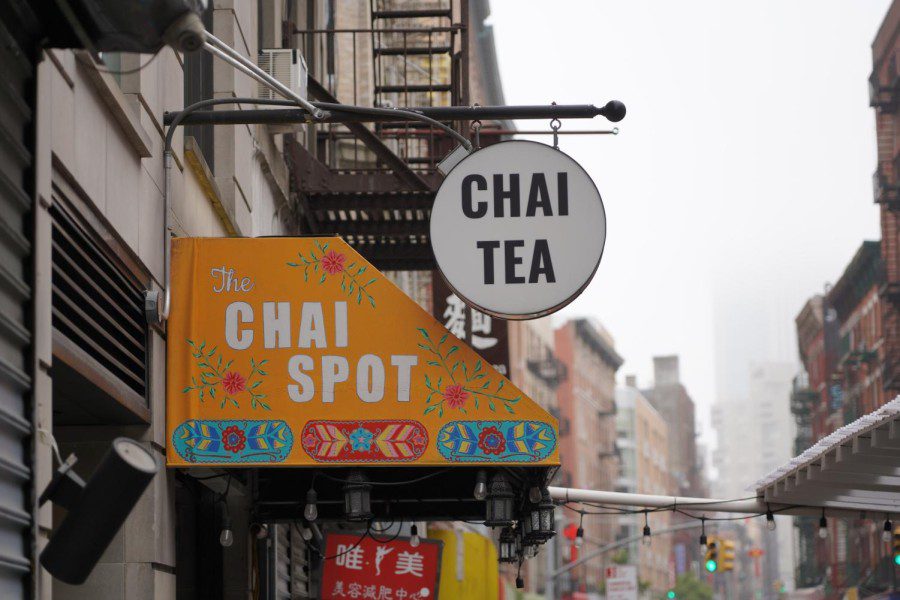 The yellow roof of The Chai Spot. Above it, is a black pole with a circular white sign that reads “Chai Tea.”