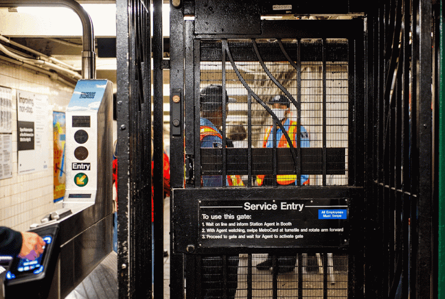 The emergency exit door at the entrance to a subway station. Behind the door there are security guards. The door has a sign that reads “Service Entry”.