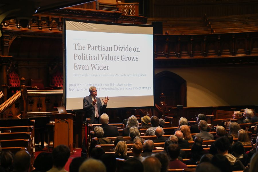 Dr. Jonathan Haidt speaking in front of an audience with a presentation labeled “The Partisan Divide on Political Values Grows Even Wider” behind him.