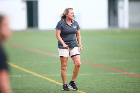 Kim Wyant, the coach of NYU’s men‘s soccer team, stands at the sidelines of a soccer pitch.