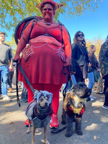A woman dressed as “Game of Thrones'' character Dragon Caraxes leashes two dogs dressed in matching “Game of Thrones” costume.