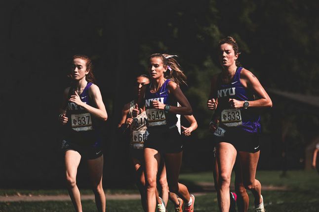Viv Kane, Grace Richardson and Janie Cooper run on the cross country track at the Connecticut College Invitational in New London, Connecticut, wearing purple N.Y.U jerseys.