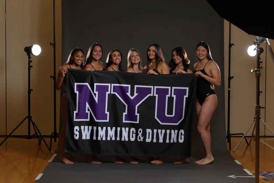 NYU Womens Swimming and Diving team pose for photo wearing their black swimsuits.